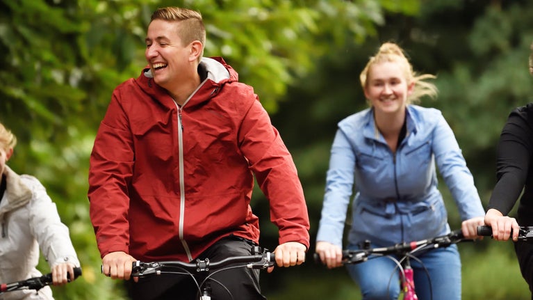 People smiling while they ride their bikes at Clumber Park